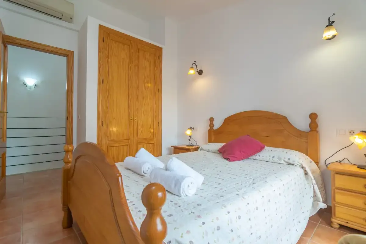 A bedroom with a wooden bed, patterned bedding, and folded towels.