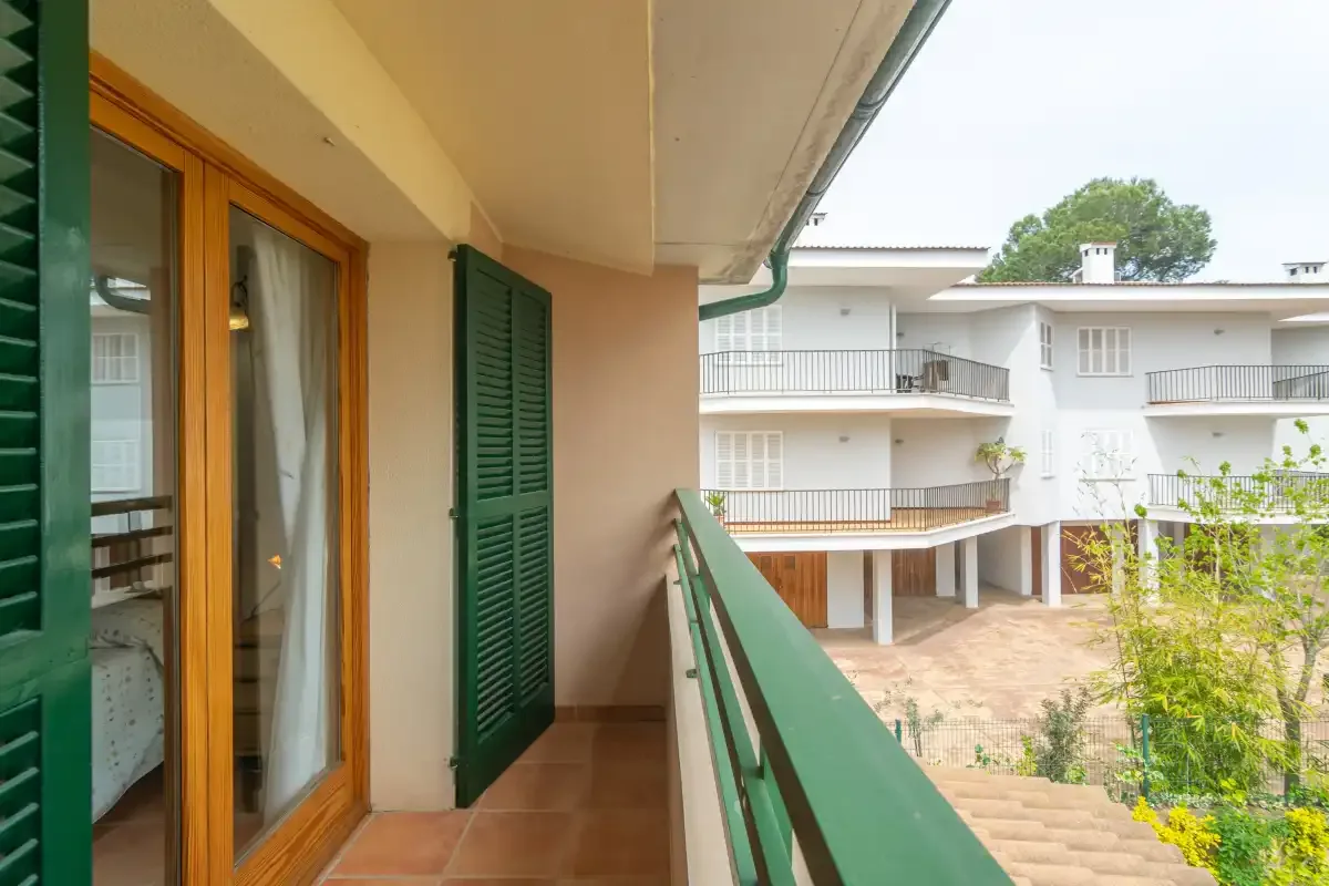 A narrow balcony overlooks a courtyard and a white building.