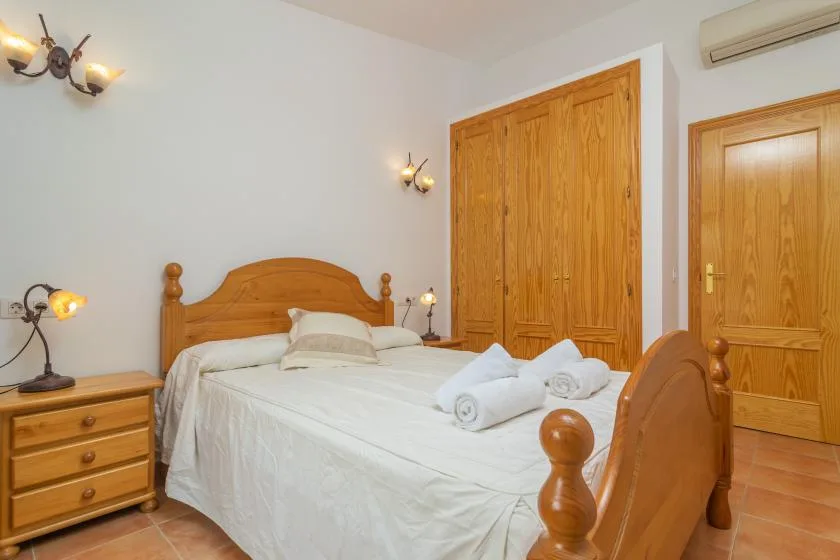 A bedroom with a wooden bed, white bedding, and matching wooden storage.