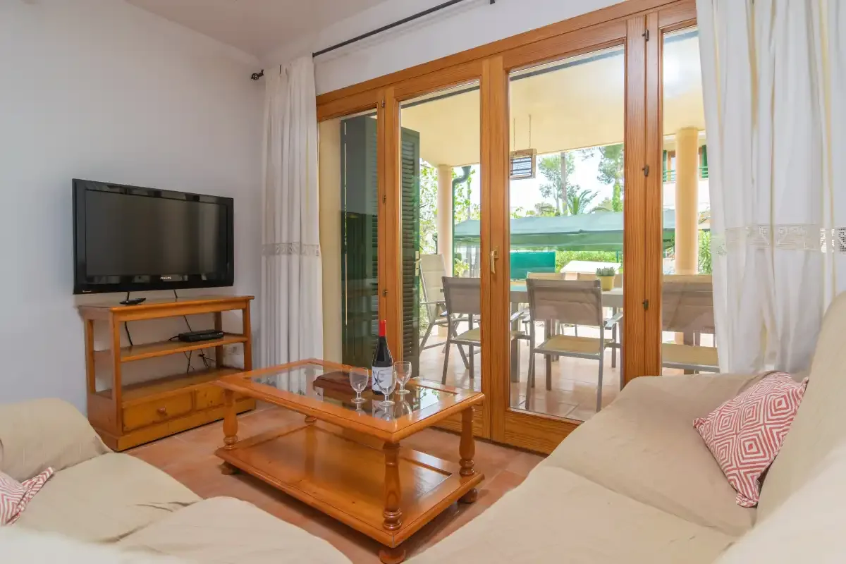 A living room with seating, a television, and glass doors opening onto a patio.