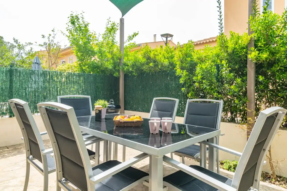 An outdoor patio dining area with a table and seating beneath an umbrella.