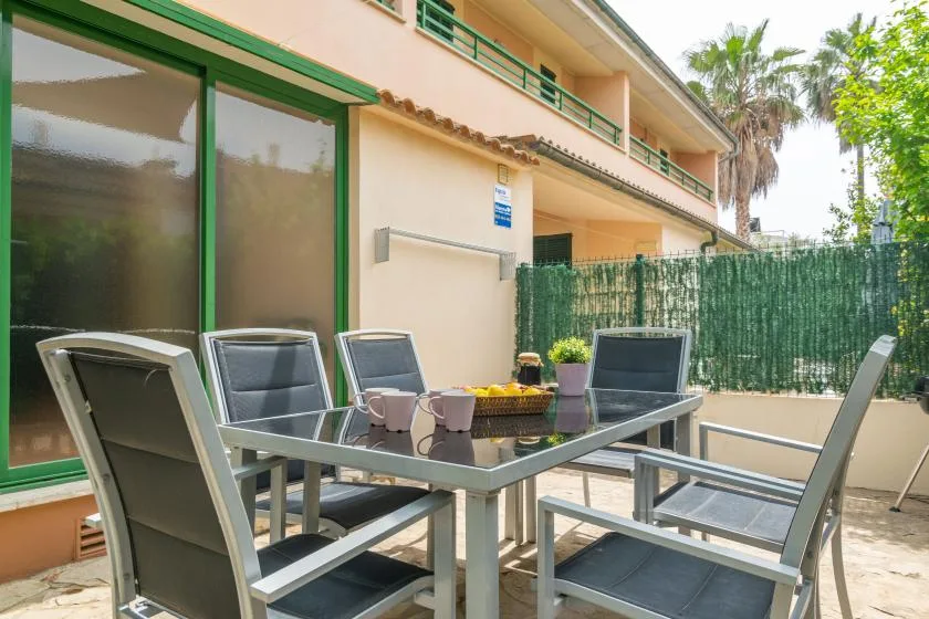 An outdoor patio dining area with a glass table and surrounding seating.