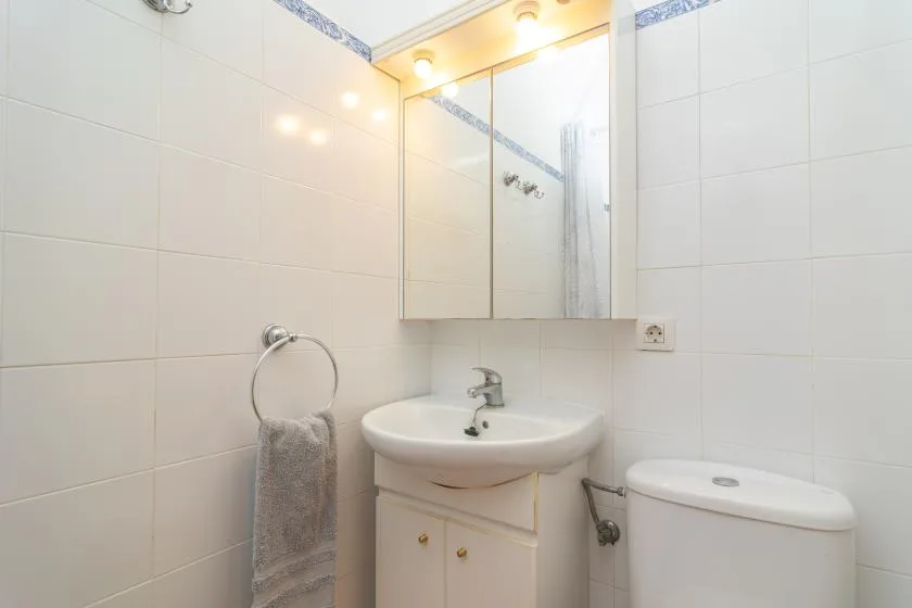 A tiled bathroom with a sink, mirror, and toilet.