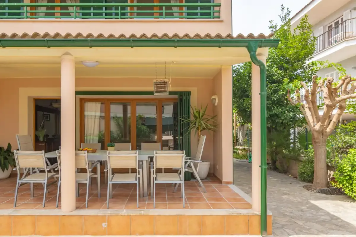 A covered patio dining area opens onto a courtyard with trees.