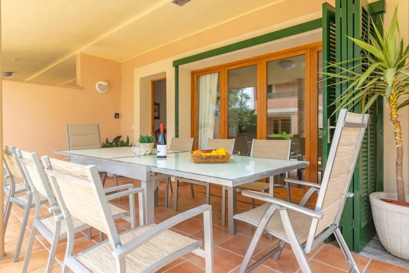 An outdoor dining area with a long table, seating, and a potted plant.
