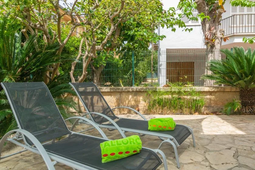 An outdoor patio with lounge seating, leafy plants, and trees.