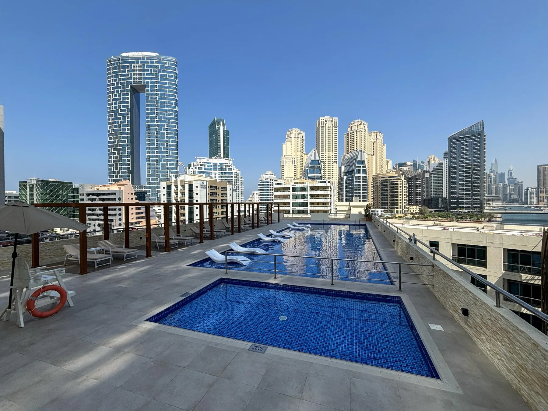 Una piscina en la azotea ofrece vistas de varios edificios altos bajo un cielo despejado.
