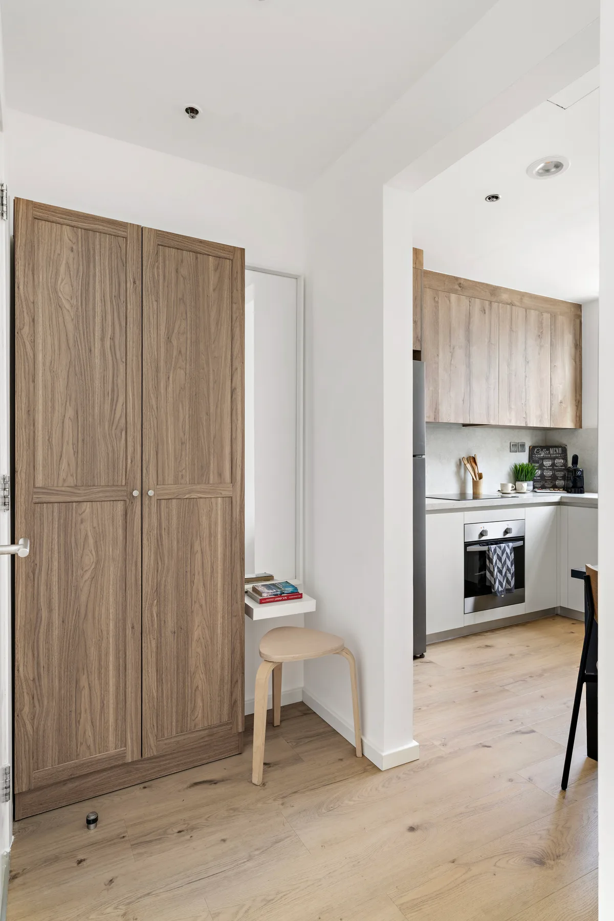 Una cocina luminosa y un pasillo contiguo con gabinetes de madera y suelo claro.