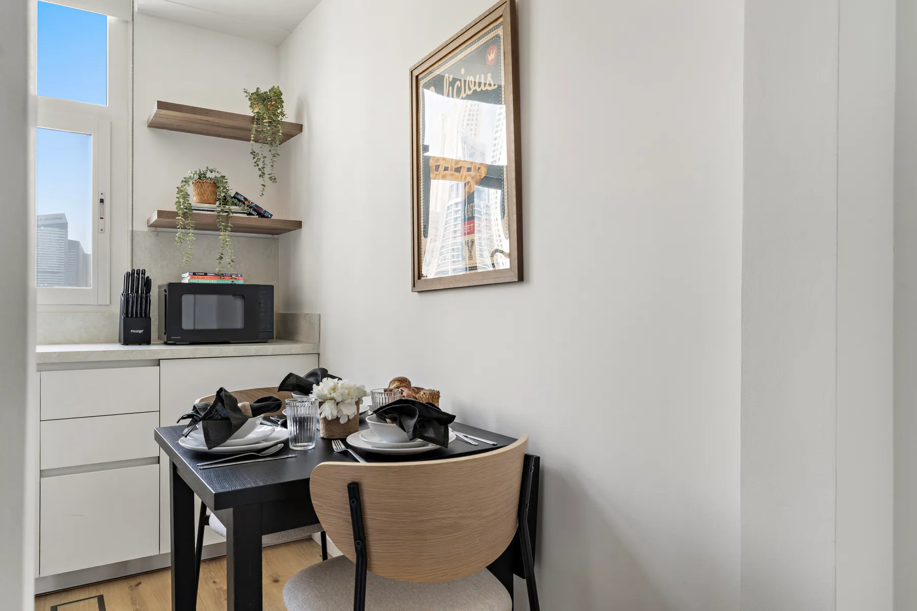 Una pequeña zona de comedor con mesa y sillas junto a una cocina compacta.