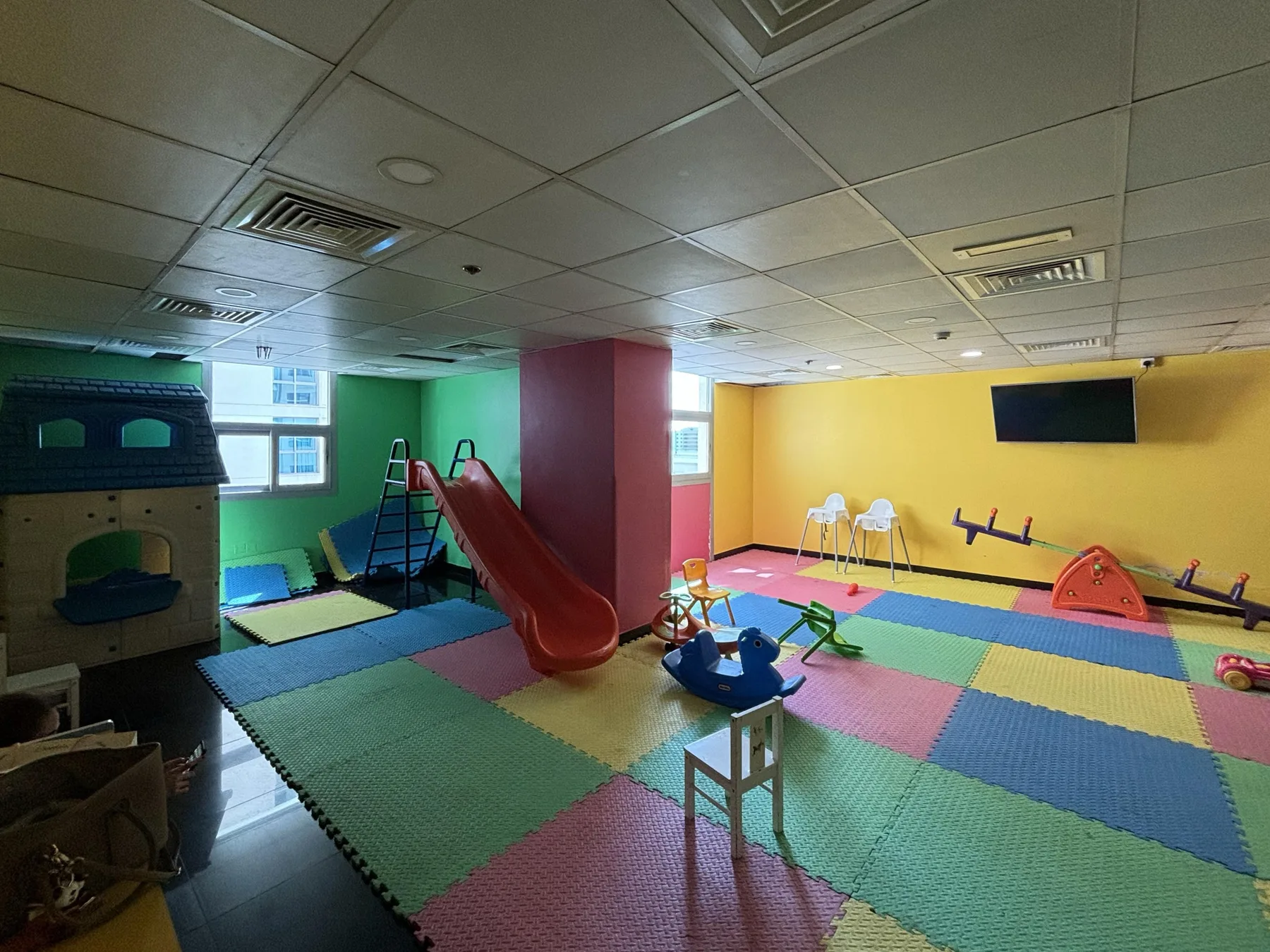 Una sala de juegos colorida tiene colchonetas acolchadas y un tobogán.