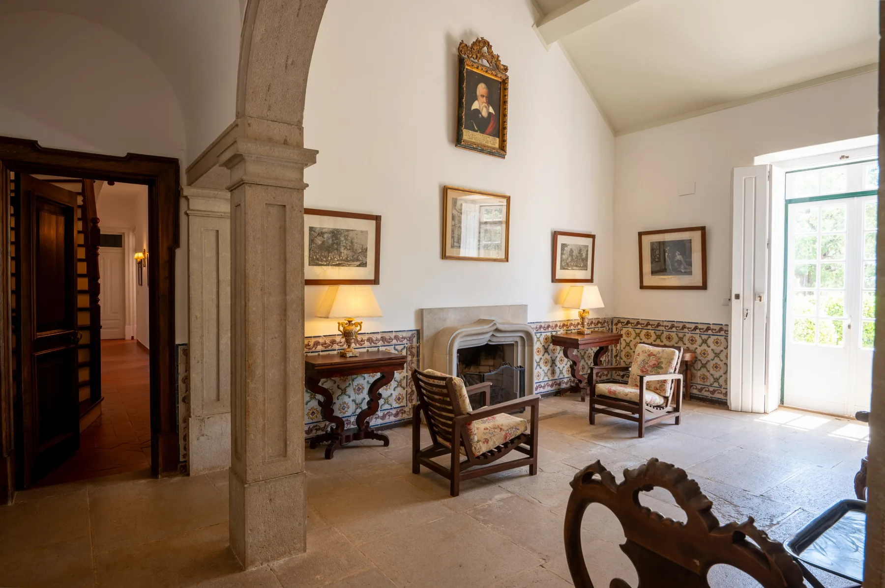 Una sala de estar con chimenea, azulejos estampados y una ventana luminosa.
