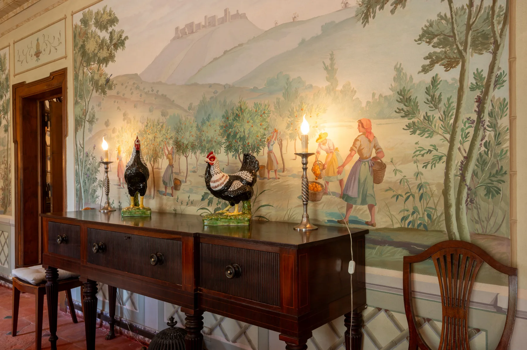 Un comedor con un aparador de madera oscura frente a un mural pintado.