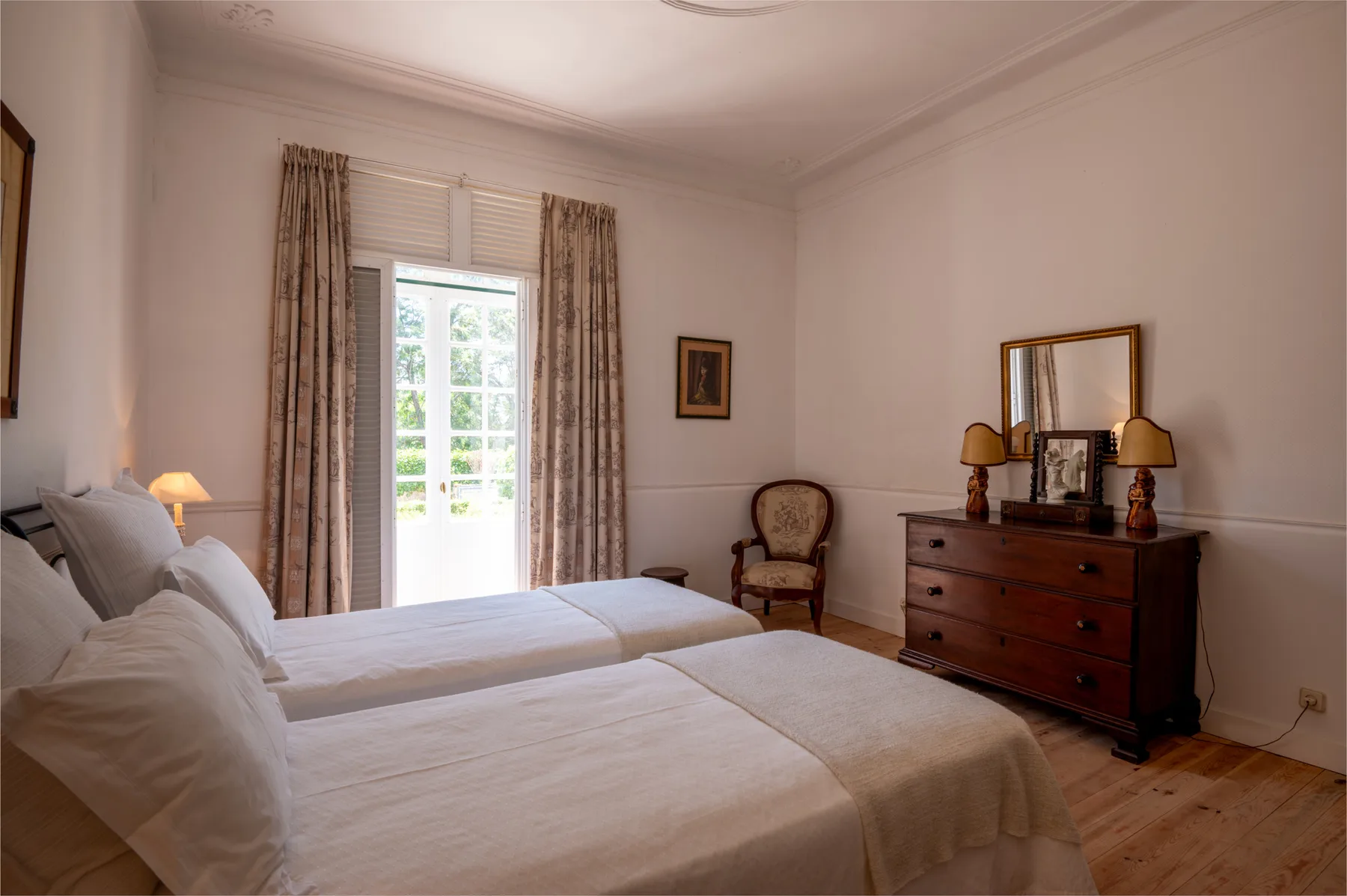 Un dormitorio luminoso con camas bien hechas y una cómoda de madera.
