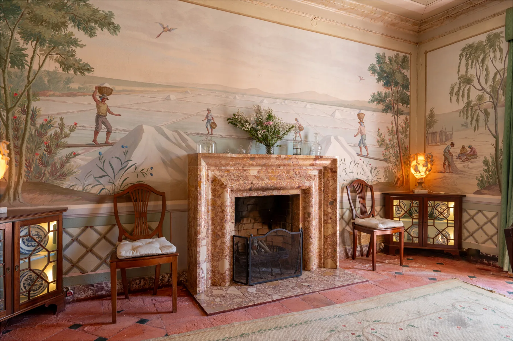 Una sala de estar con chimenea, mural decorado y sillas.