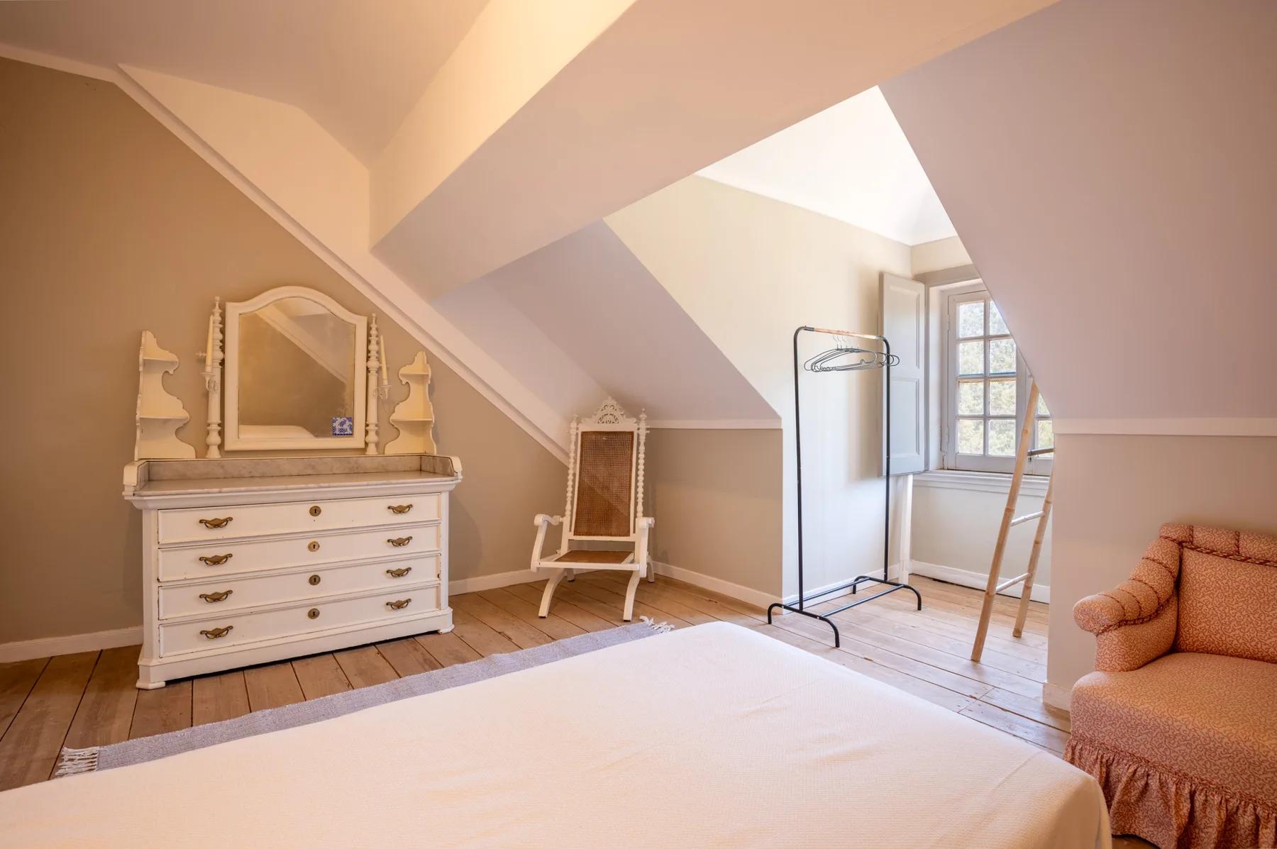 Un dormitorio con una cama, una cómoda y un techo inclinado.