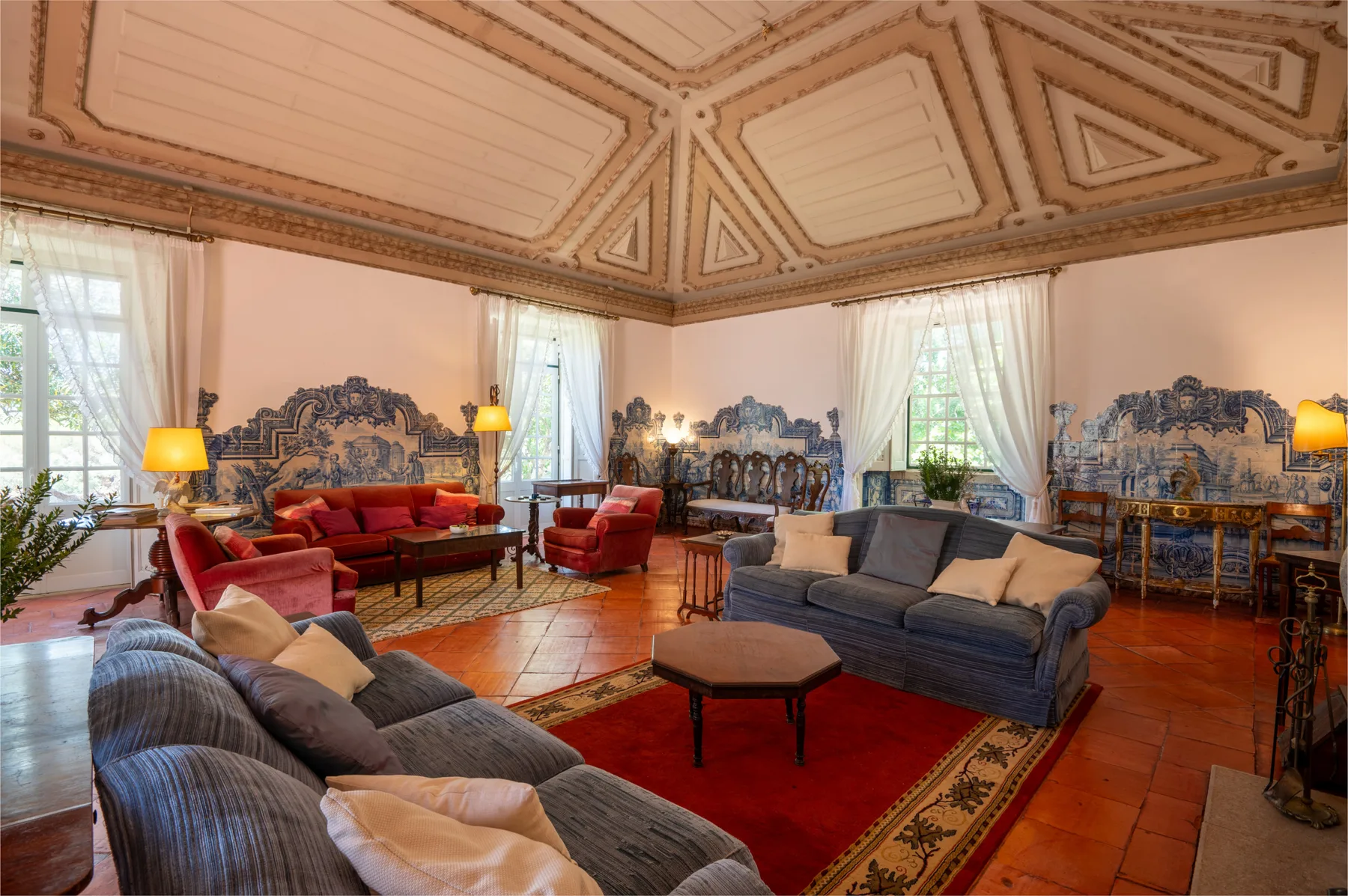 A sitting room with several seating areas arranged around a red rug.