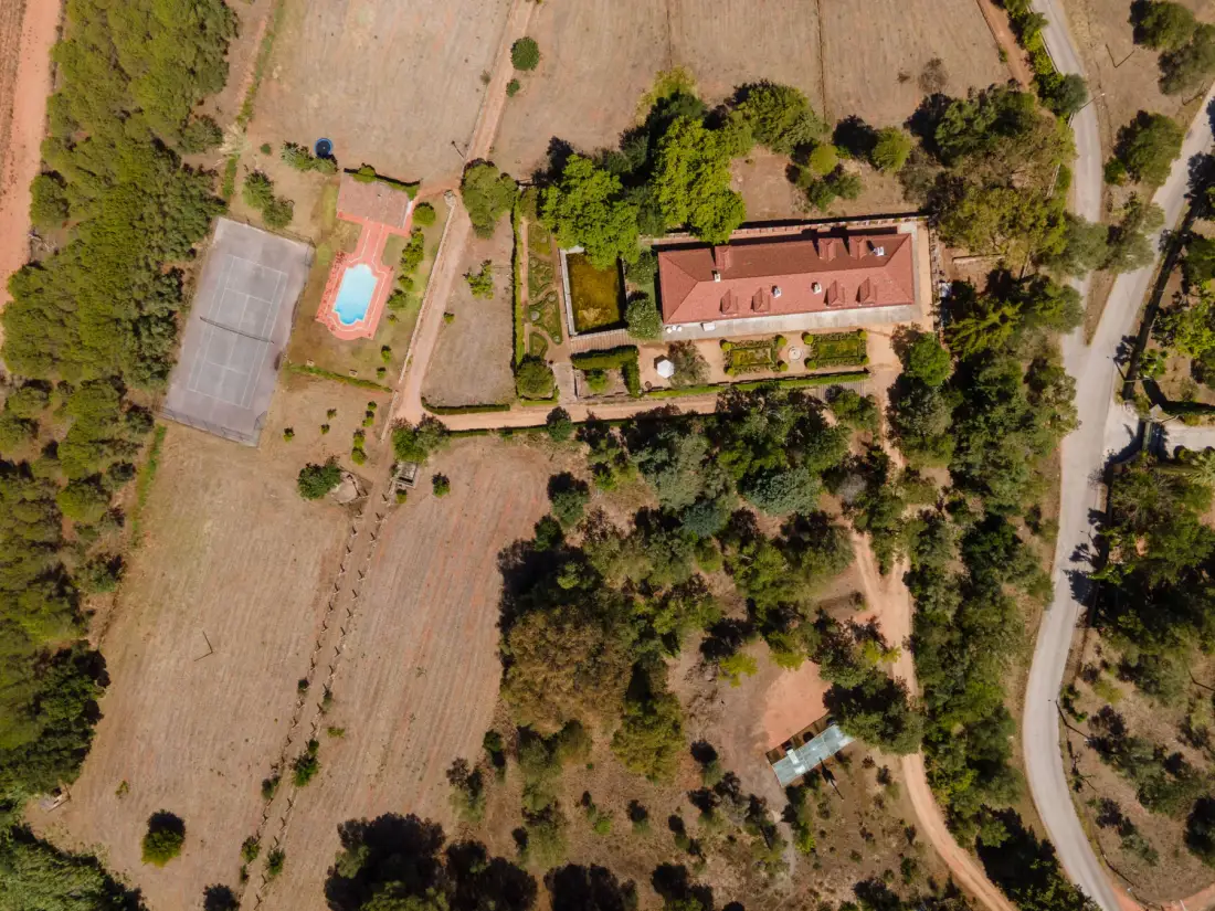 Vista aérea de una propiedad rural con un edificio alargado y una piscina.