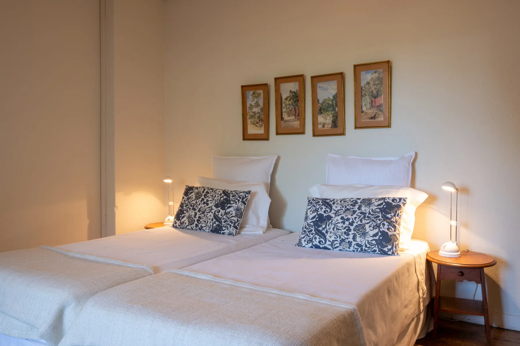 Un dormitorio con dos camas bien arregladas y cuadros enmarcados en la pared.