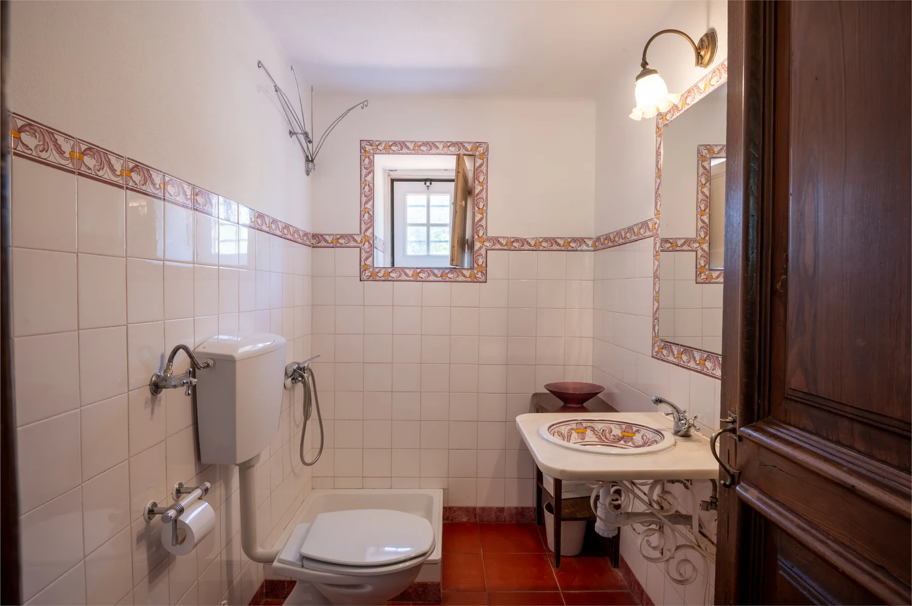 Un baño con azulejos, inodoro y lavabo bajo un espejo.