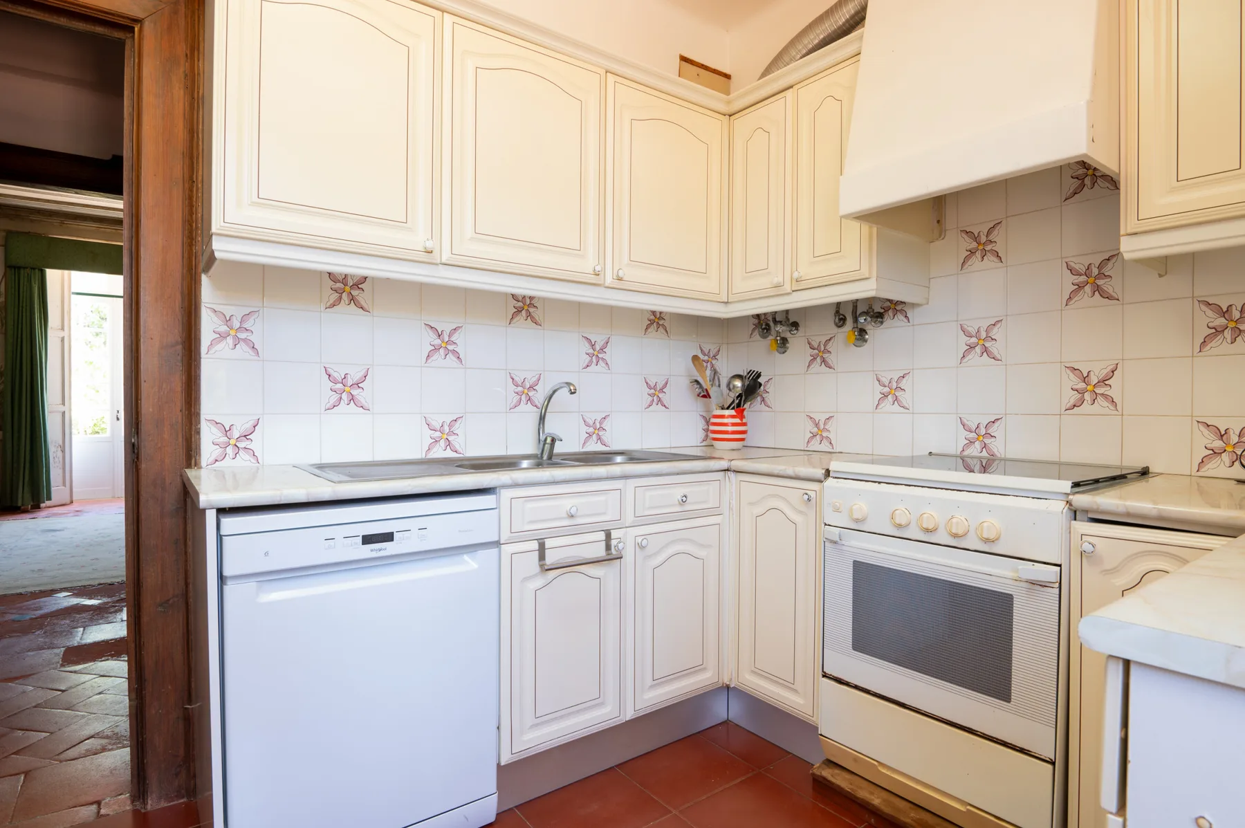 Una cocina luminosa con gabinetes blancos y azulejos estampados.