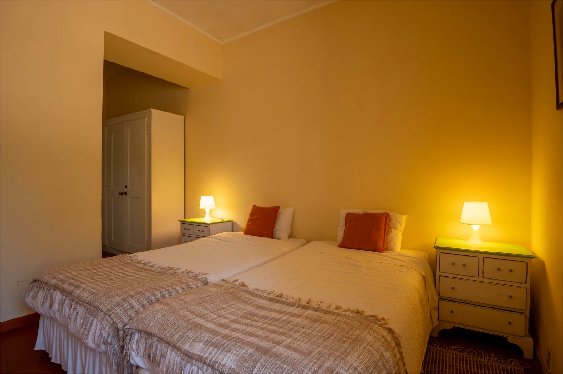 Un dormitorio con dos camas, lámparas de noche y una cómoda.