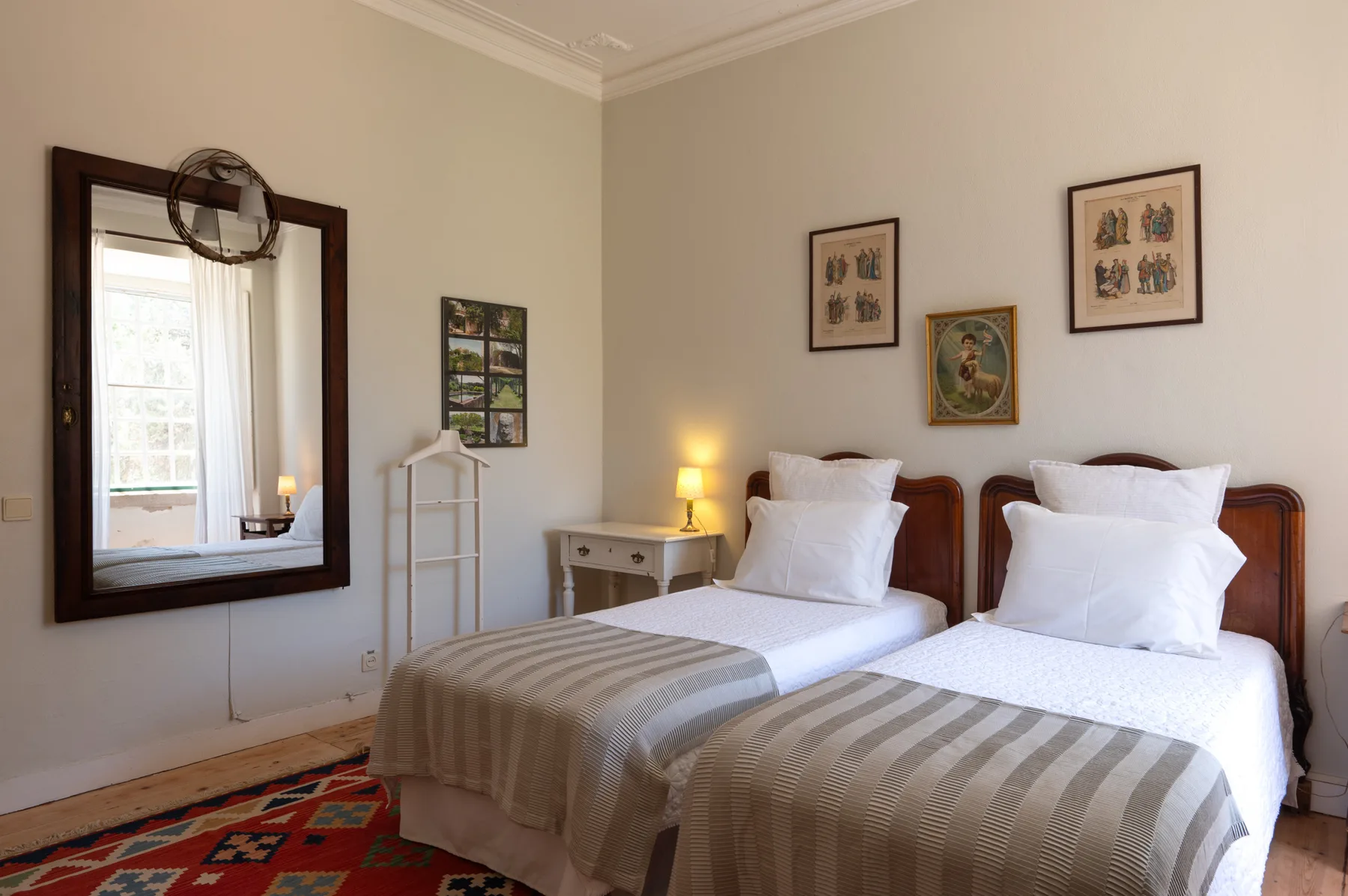 Un dormitorio con dos camas individuales, mesitas de noche y cuadros en la pared.