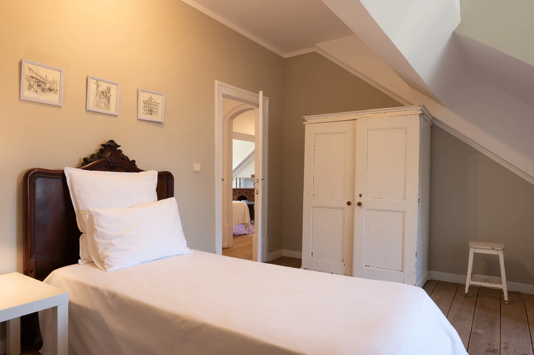 Un dormitorio con una cama, un armario y cuadros en la pared.