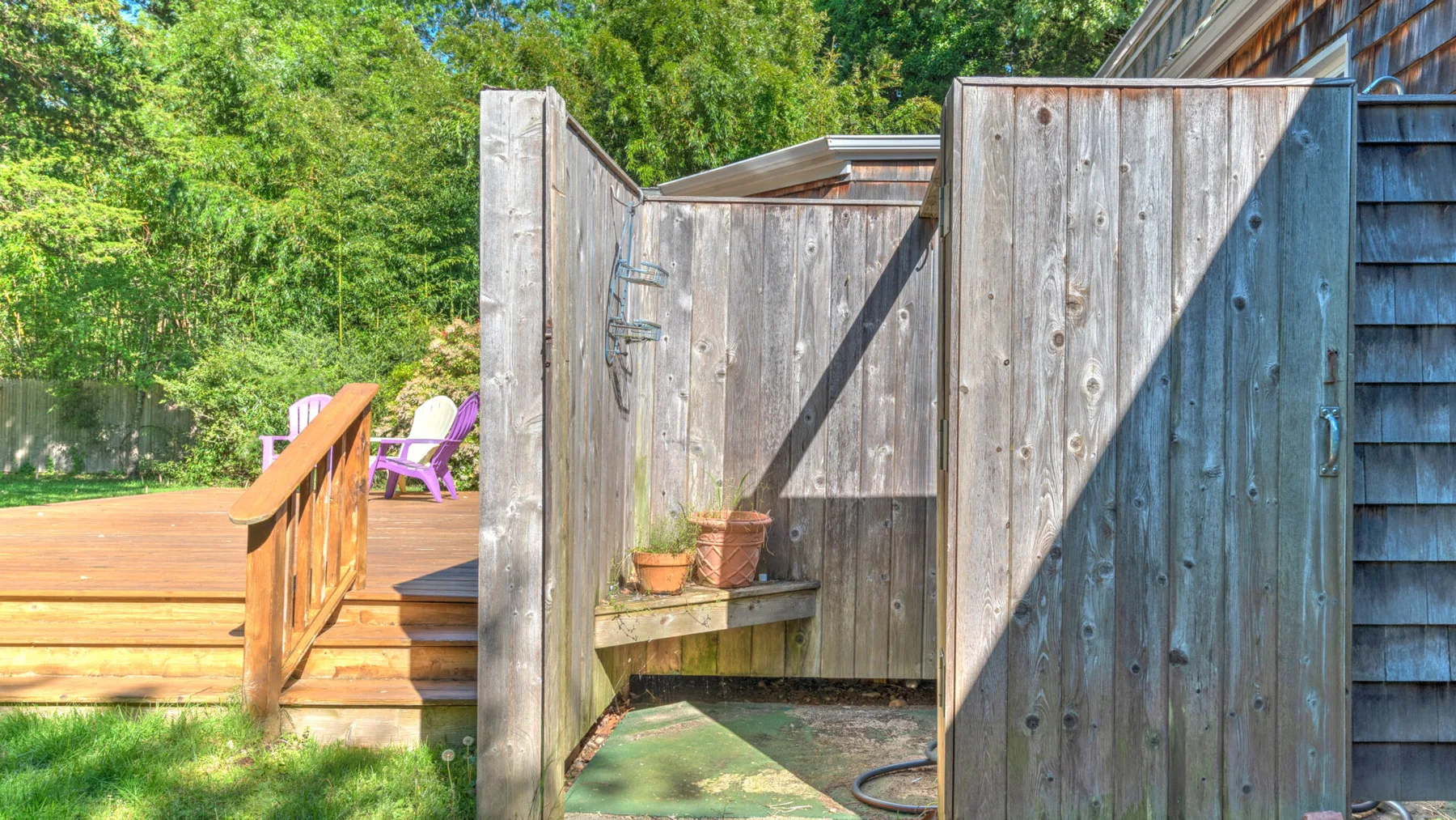 An outdoor shower area with a wooden privacy screen and nearby deck.