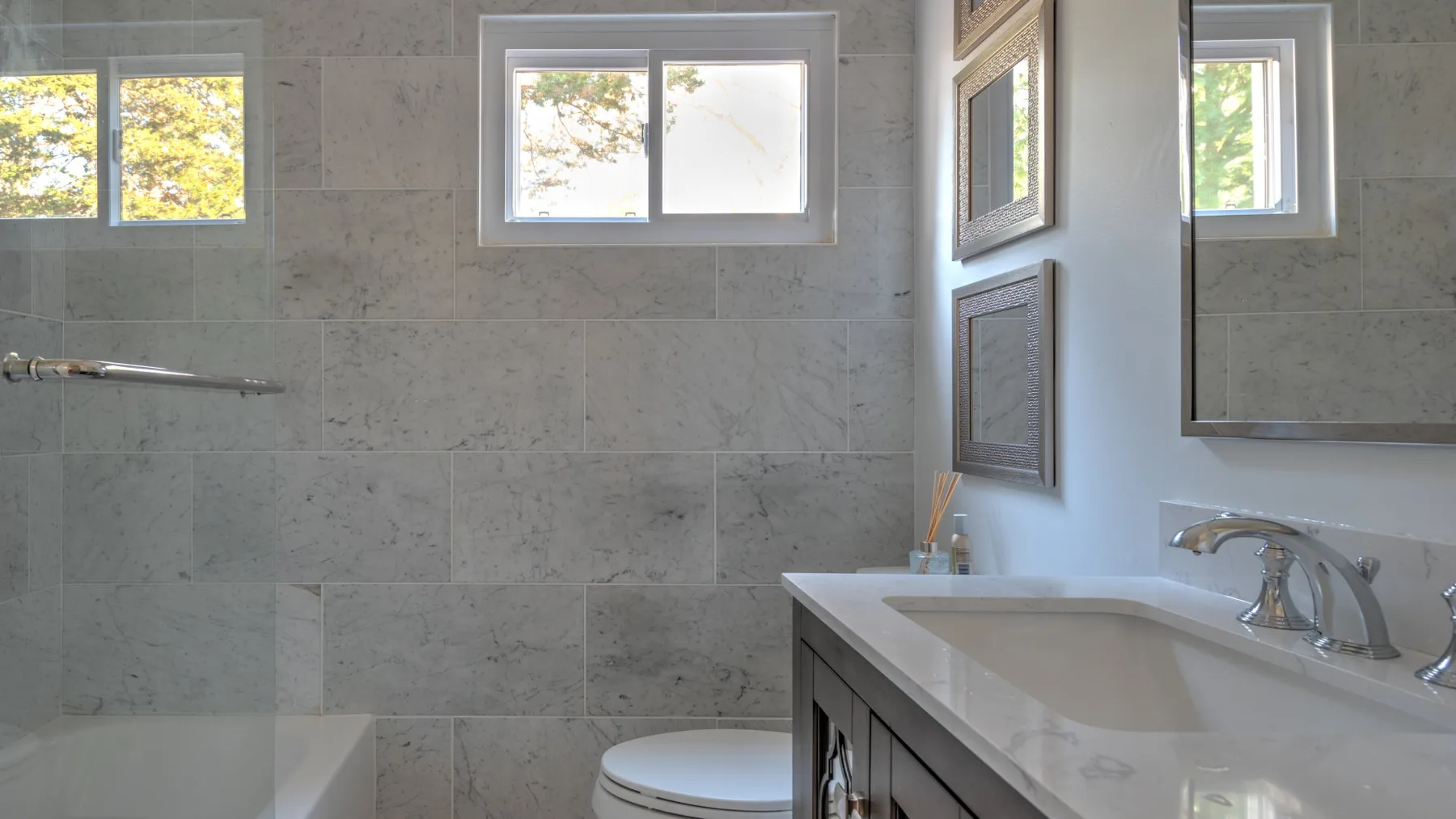 A tiled bathroom with a vanity, sink, and small windows.