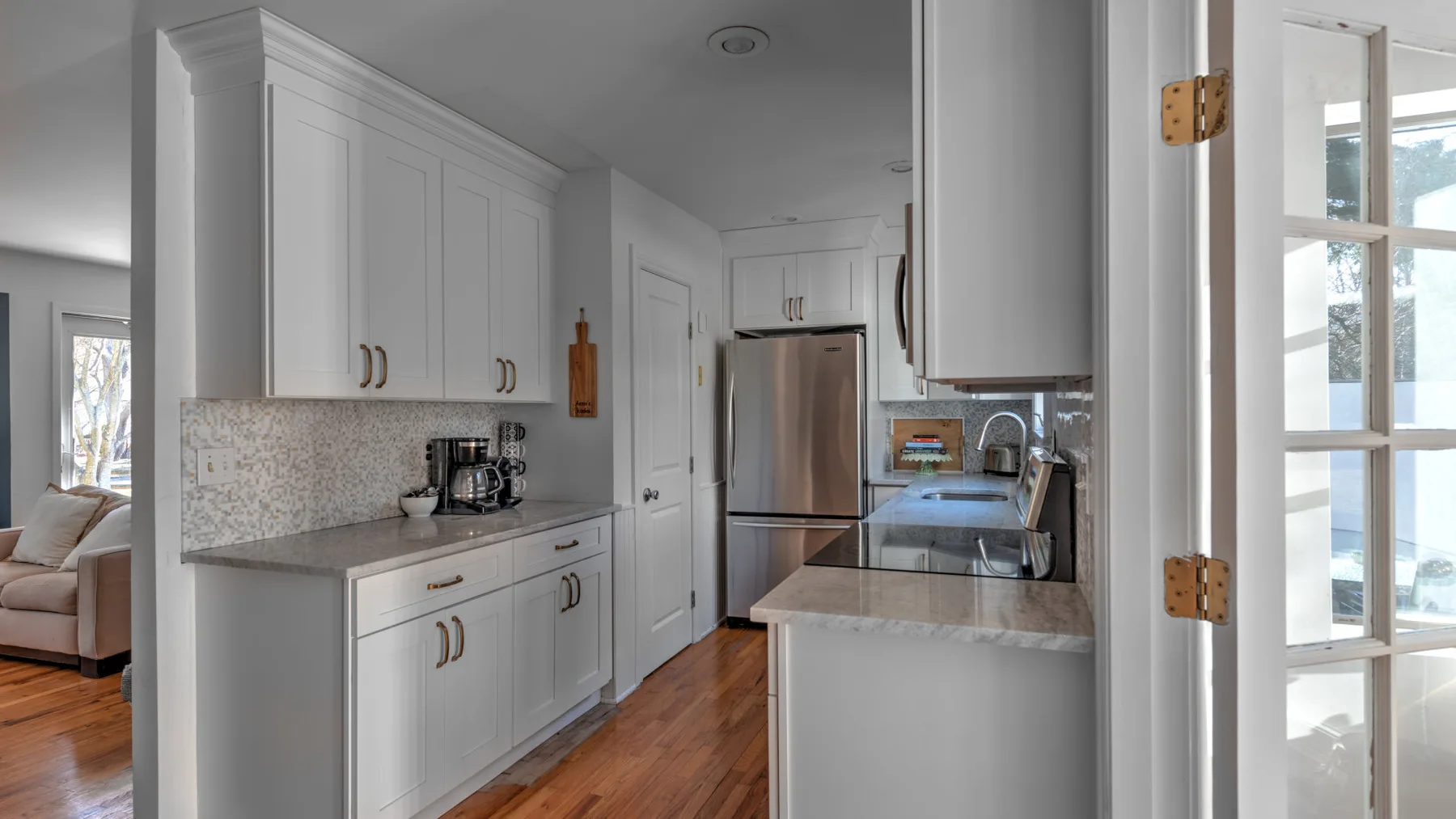 A bright kitchen with white cabinets, stainless steel appliances, and a stone countertop.