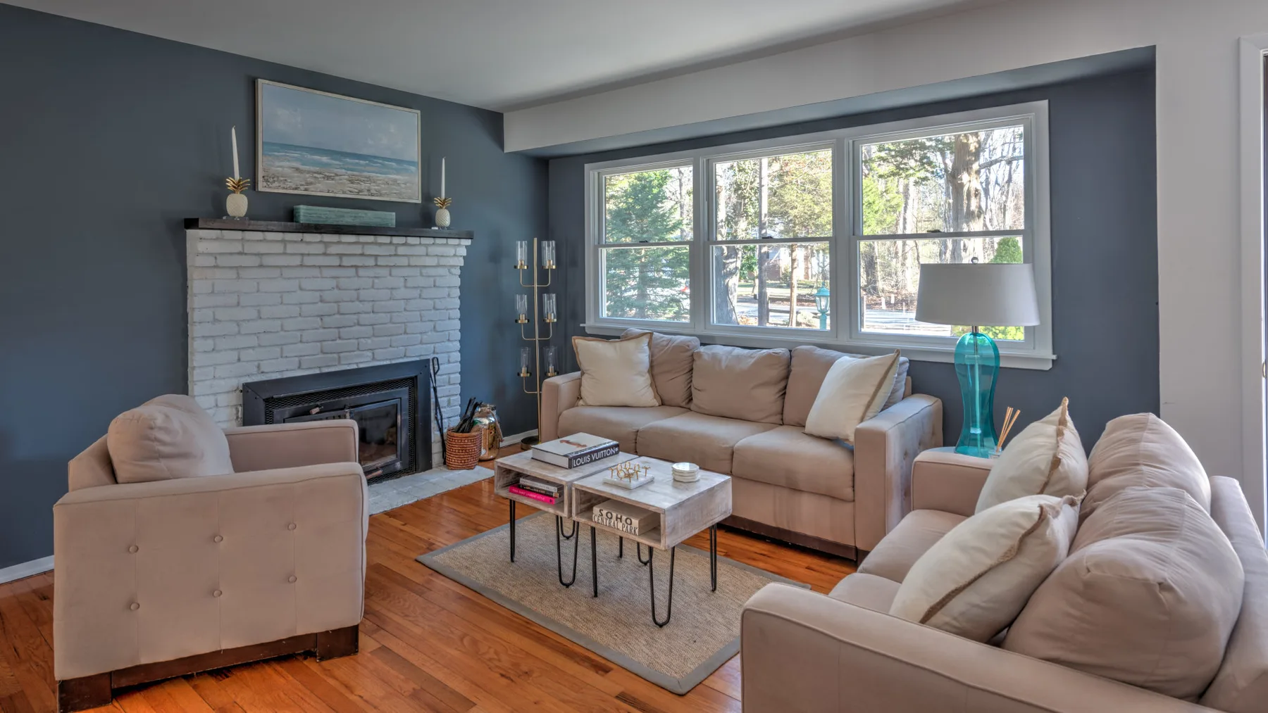 A living room with beige seating, a fireplace, and large windows.