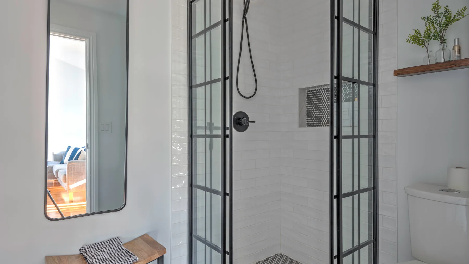 A tiled bathroom with a glass shower enclosure and a wall mirror.