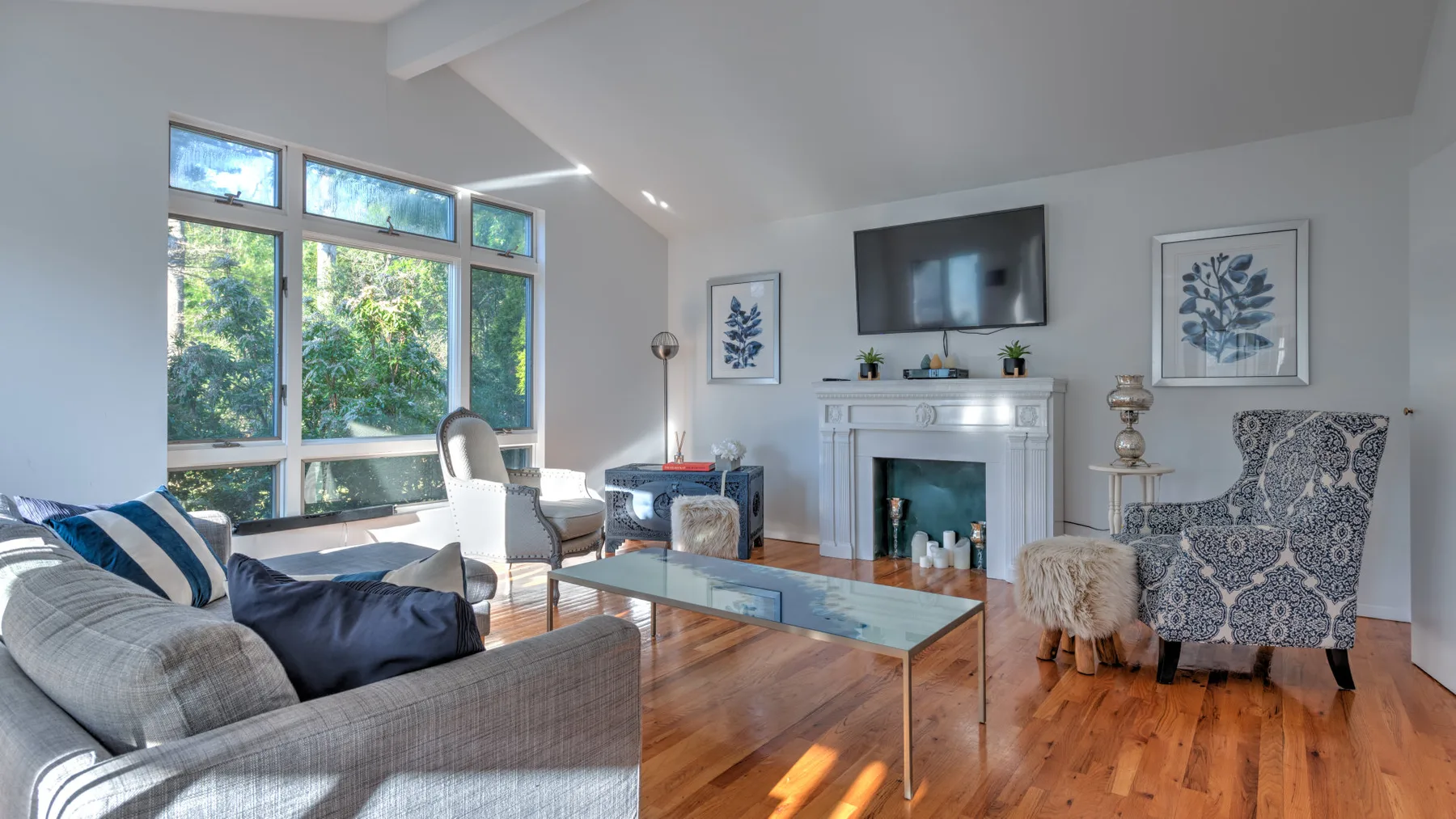A bright living room with seating, a fireplace, and large windows.