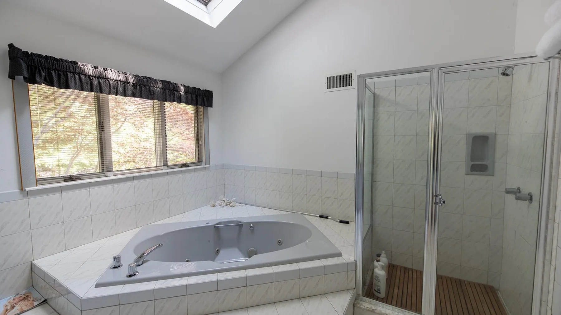Un baño tiene una bañera empotrada junto a una ducha con mampara de vidrio.