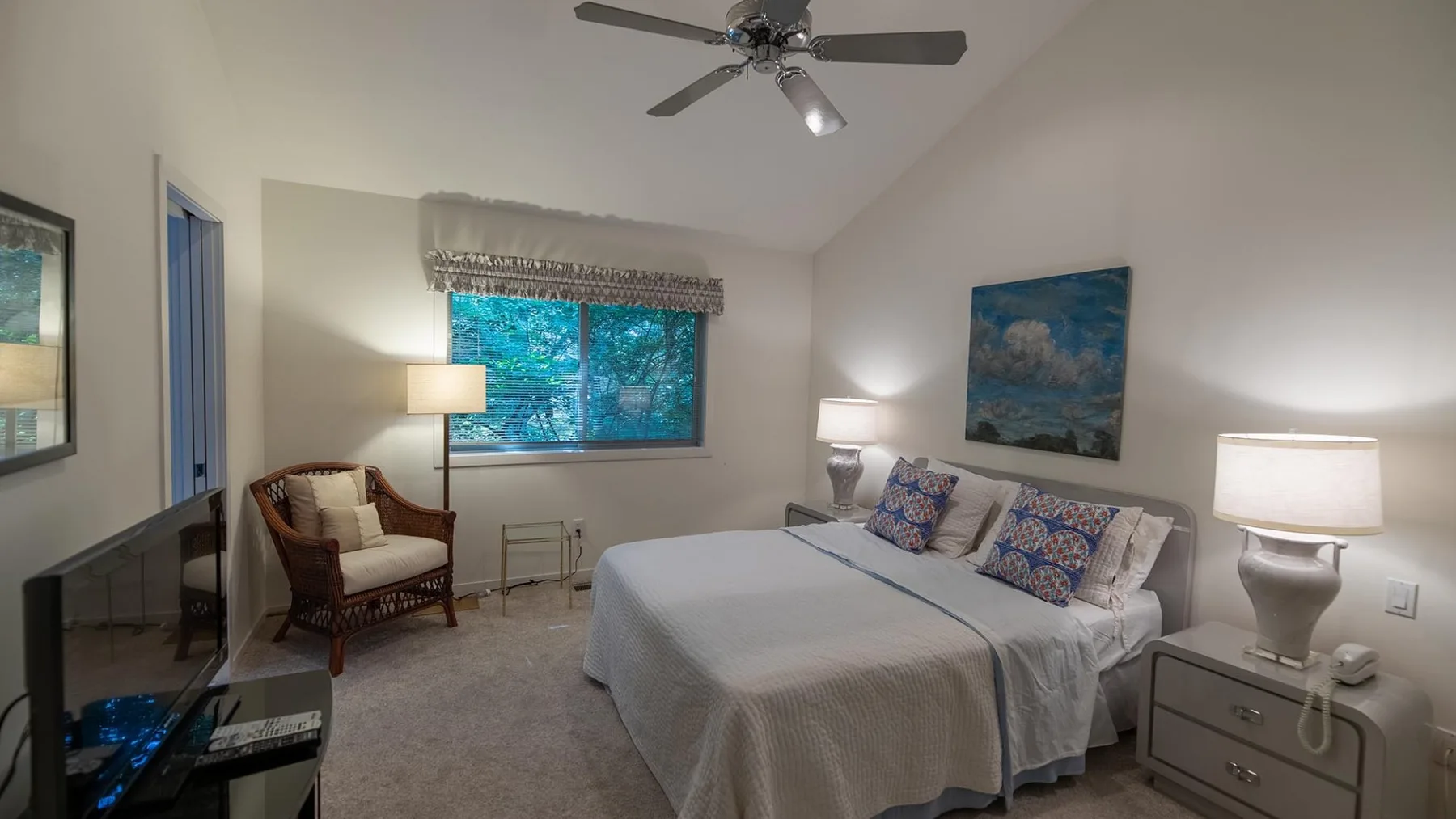 Un dormitorio con una cama, una ventana y un ventilador de techo.