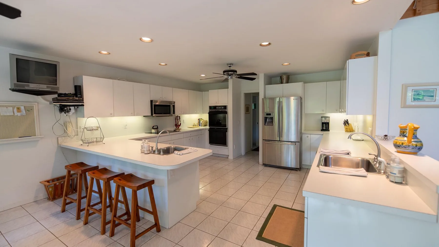 Una cocina luminosa con gabinetes blancos, una isla central y un ventilador de techo.