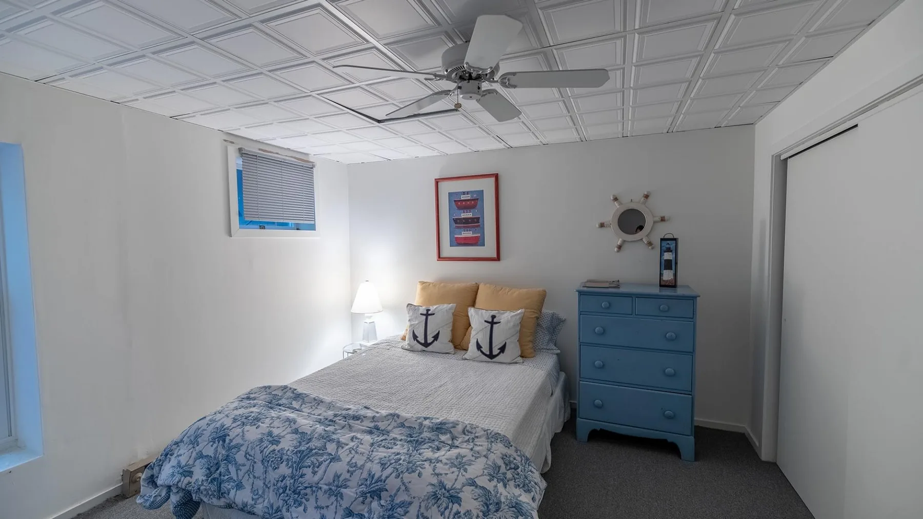 Un dormitorio con una cama, una cómoda azul y un cuadro enmarcado.