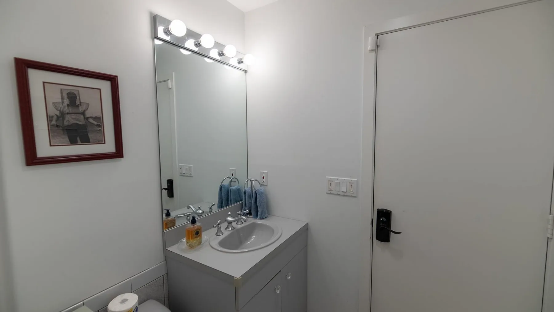 Un lavabo de baño con espejo y un cuadro enmarcado en la pared.
