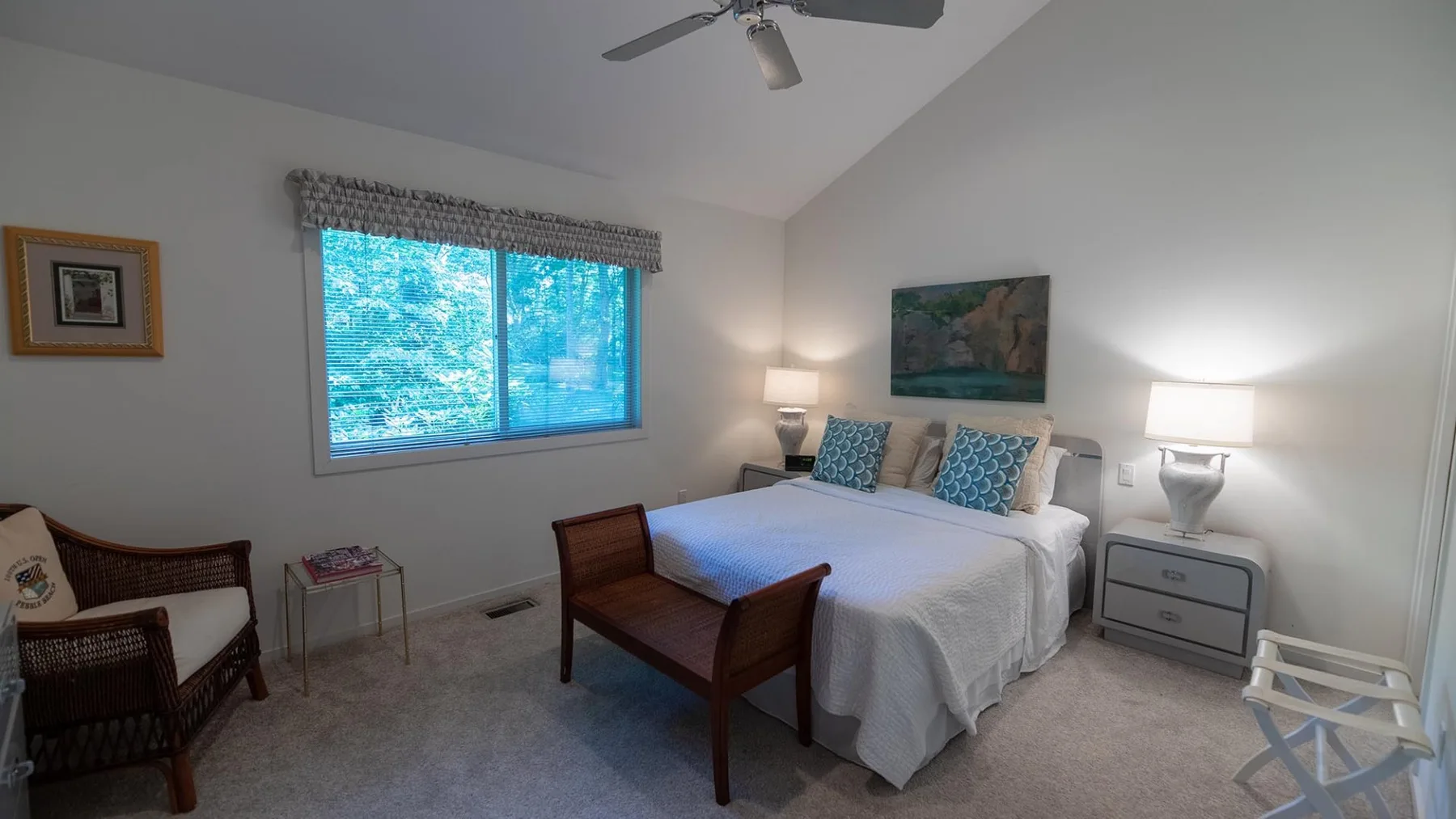 Un dormitorio con una cama, lámparas de noche y una ventana con vista a los árboles.