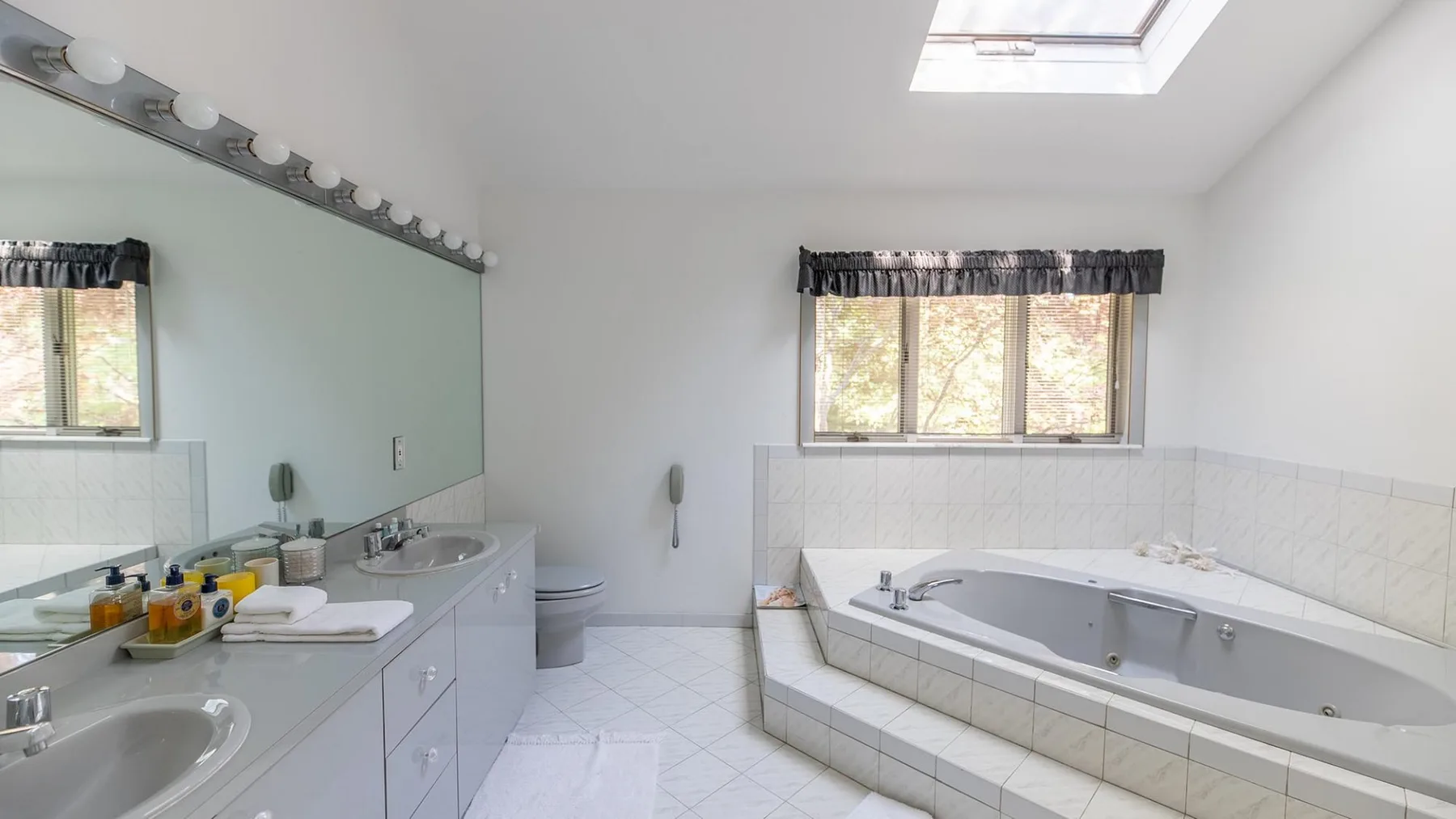 Un baño con un tocador largo y una bañera empotrada bajo una ventana.