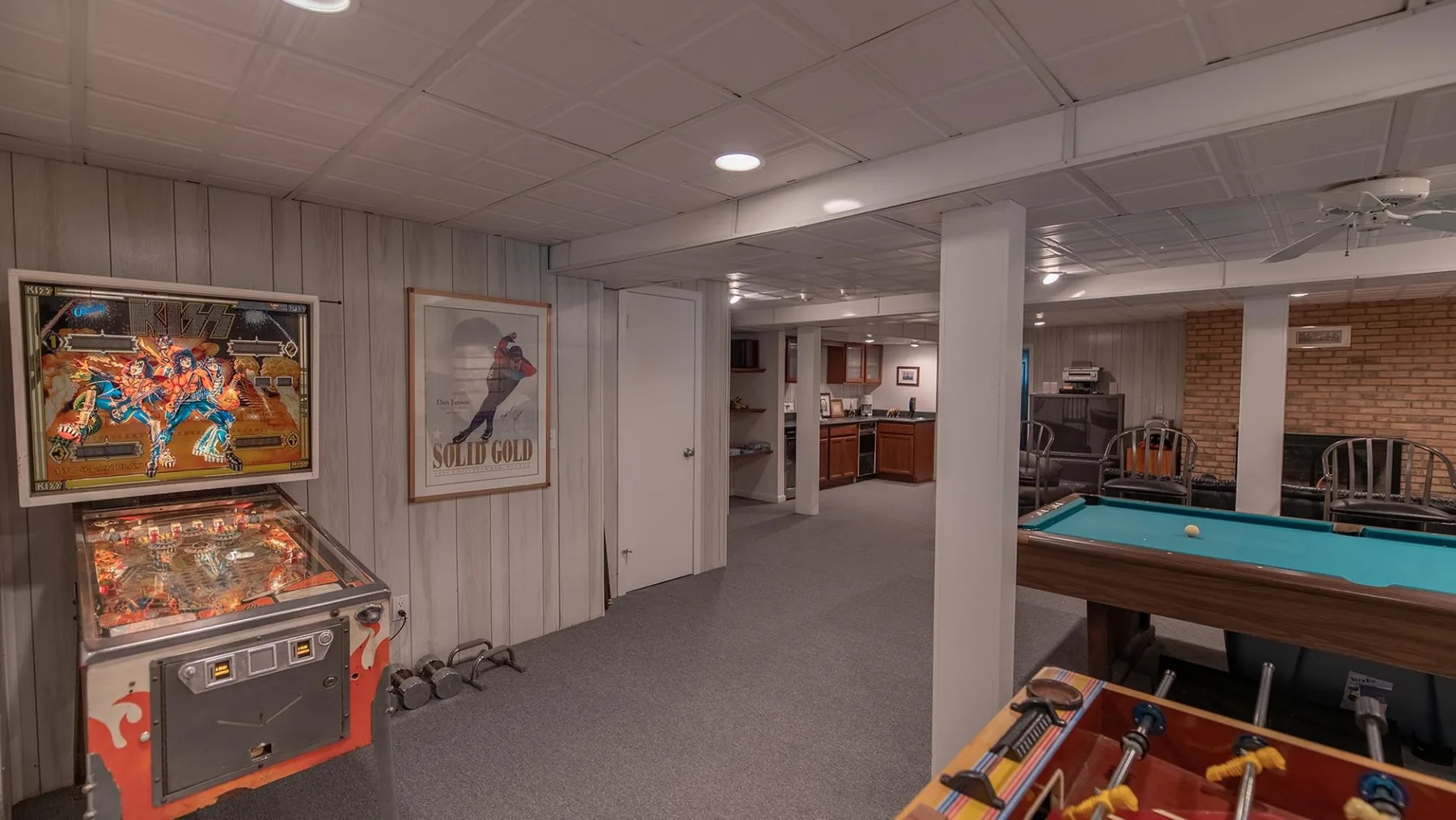Una sala de juegos en el sótano con una máquina de pinball y una mesa de billar.