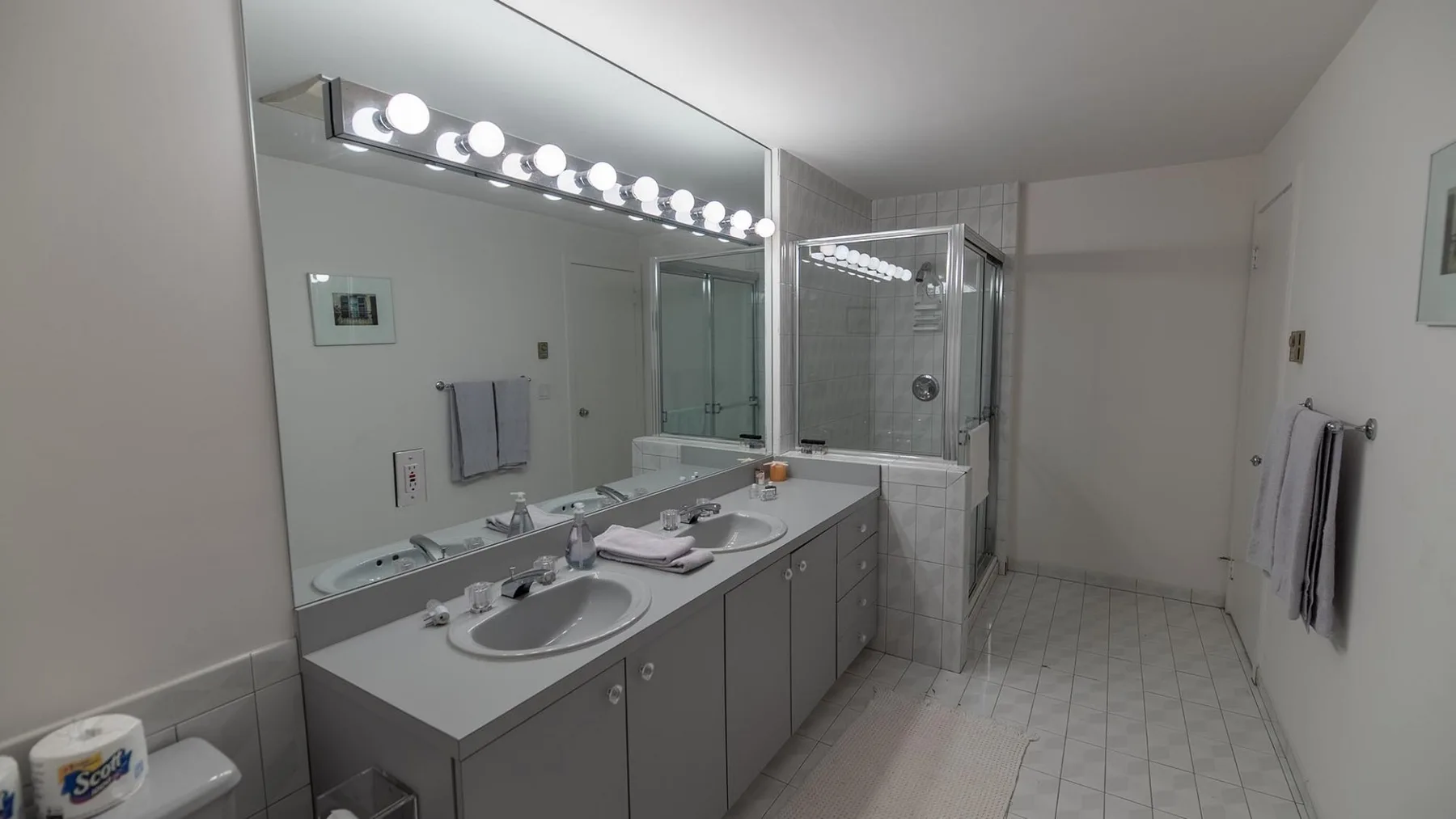 Un baño con un tocador largo, lavabos y una ducha.