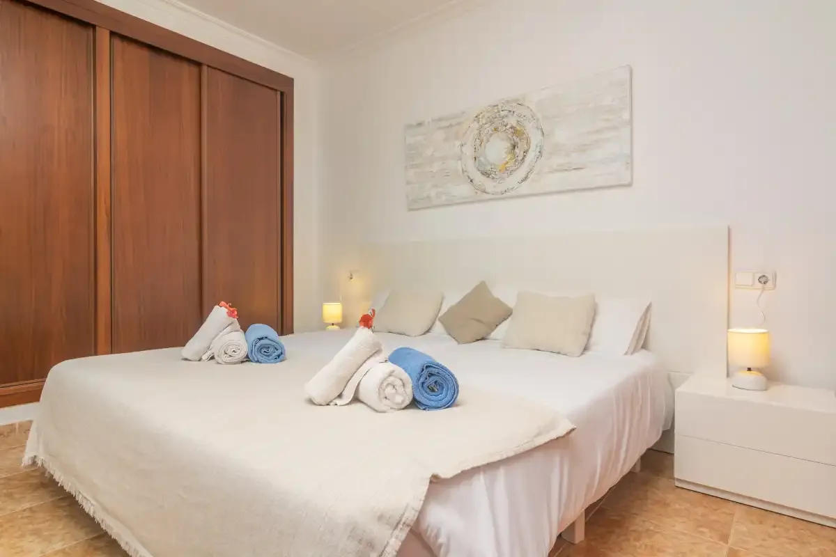 A bedroom with a neatly made bed and wooden wardrobes.