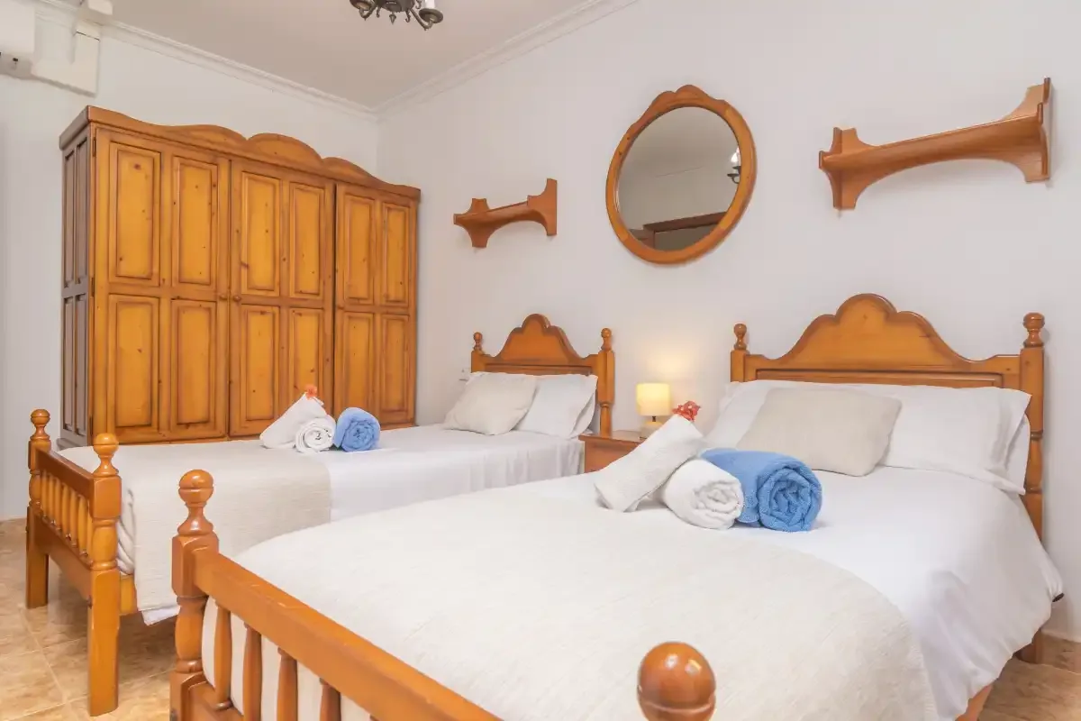 A bedroom with two beds and a wooden wardrobe.