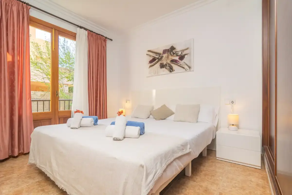 A bright bedroom with a large bed and glass doors opening onto a balcony.