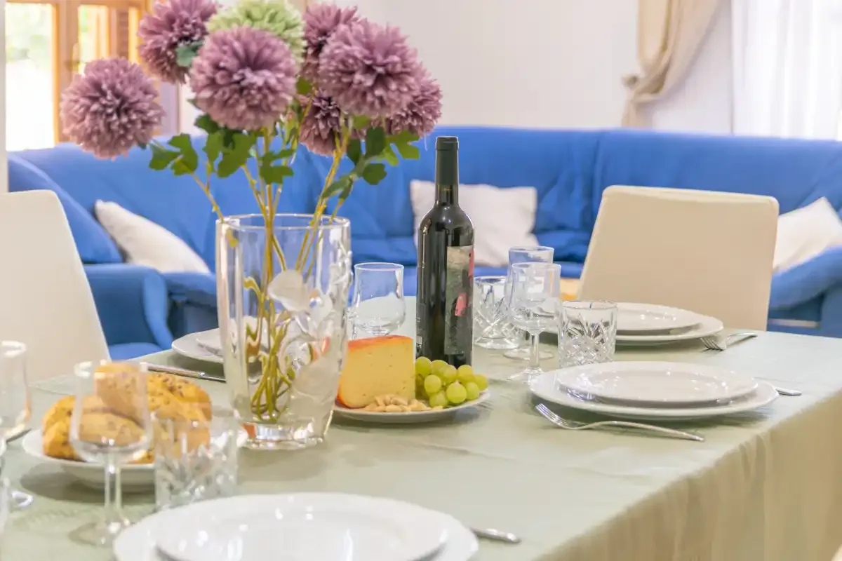 A dining table set with plates and glasses sits in front of blue seating.
