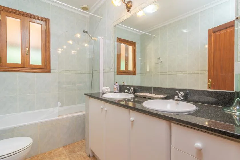 A bathroom with a bathtub, a long vanity, and a large mirror.