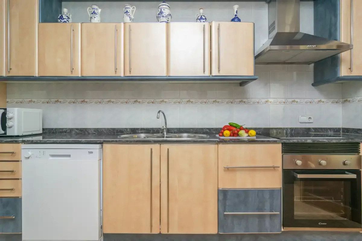 A kitchen with light wood cabinets, a sink, and an oven.