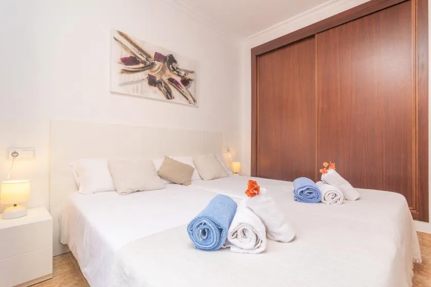 A bedroom with a neatly made bed and a large wooden wardrobe.