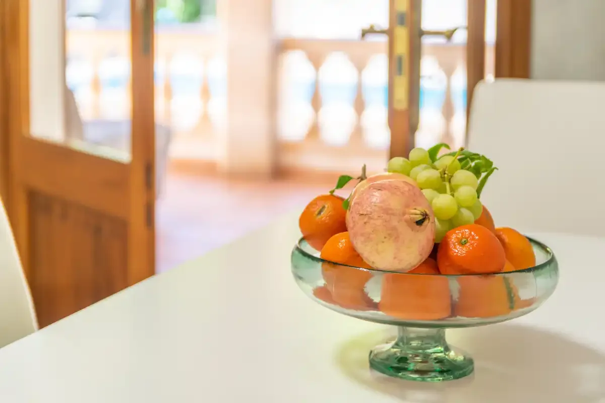 A fruit bowl sits on a table in a bright dining area.